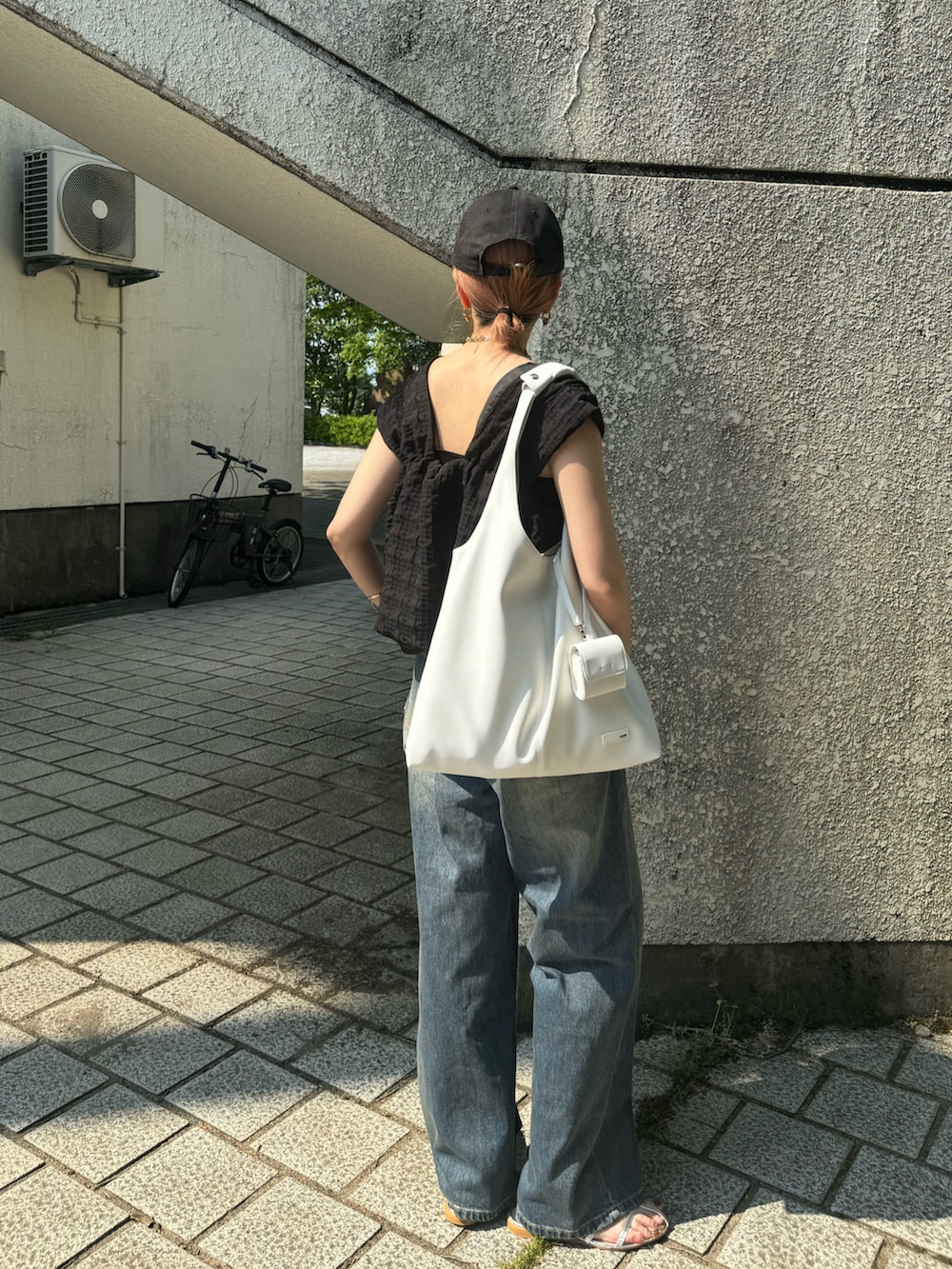 ホワイト系のトートバッグ、ブルー系のデニムパンツ、シルバー系のサンダルを着用したレディースの夏コーディネートの4枚目の写真