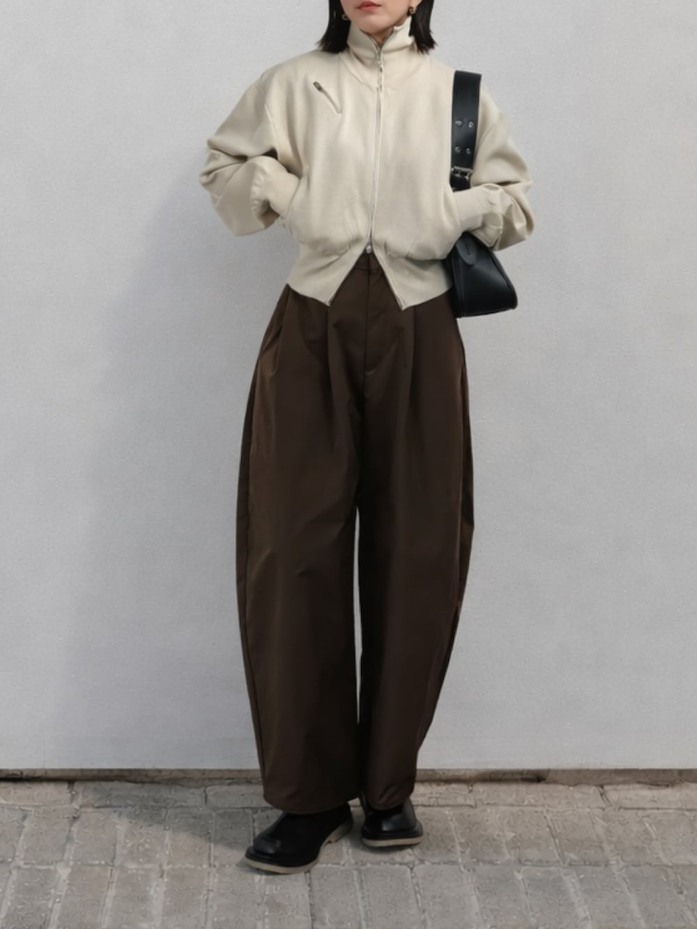 ブラウン系のその他パンツ、ベージュ系のニット/セーター、ブラック系のハンドバッグを着用したレディースの冬コーディネートの2枚目の写真