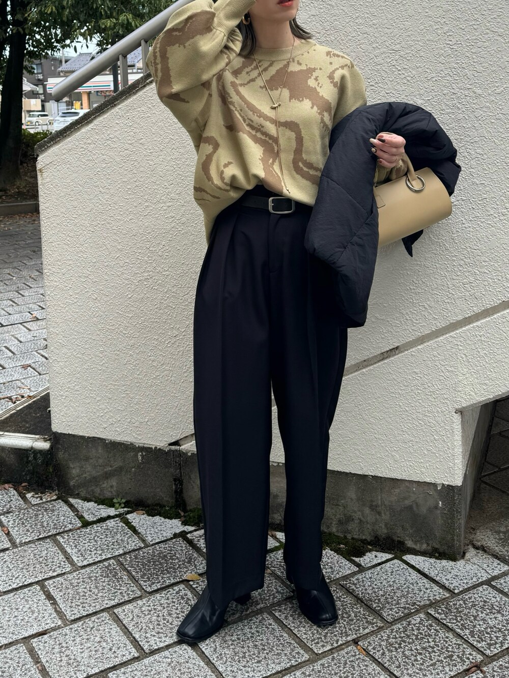 グリーン系のニット/セーター、ブラック系のその他パンツ、ベージュ系のハンドバッグを着用したレディースの秋コーディネートの2枚目の写真