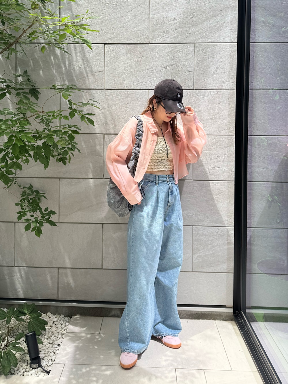 ホワイト系のタンクトップ、ブルー系のデニムパンツ、シルバー系のトートバッグを着用したレディースの夏コーディネートの3枚目の写真