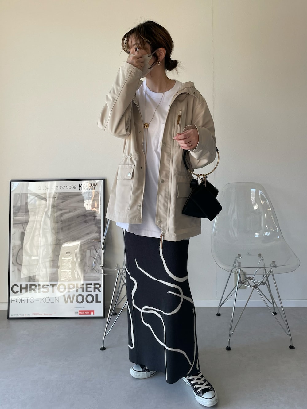 ホワイト系のマウンテンパーカー、グレー系のスカート、ブラック系のハンドバッグを着用したレディースの春コーディネートの3枚目の写真