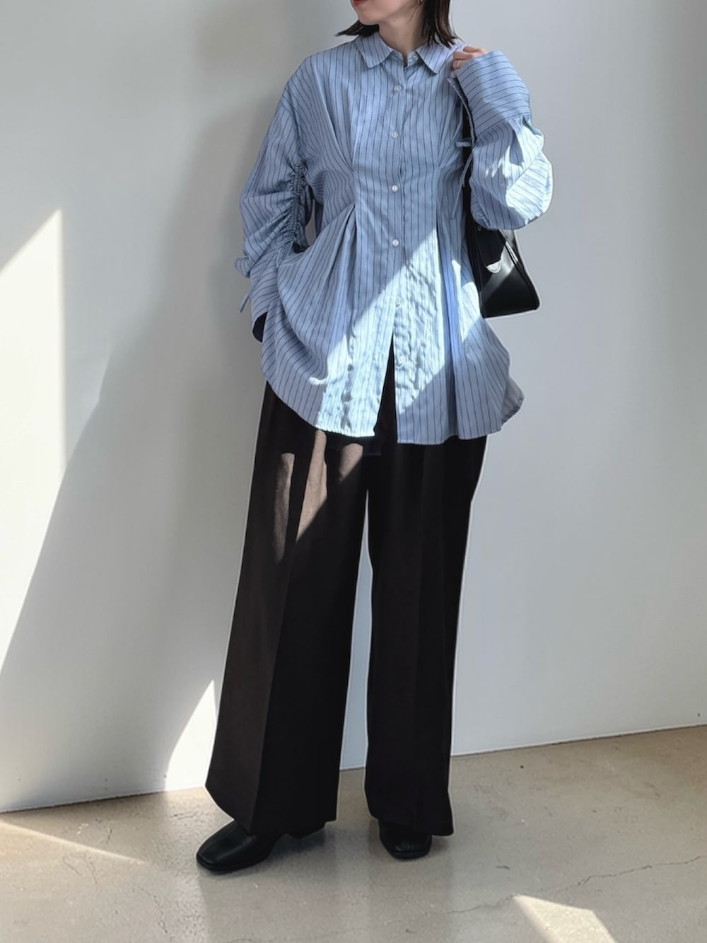 ブルー系のシャツ/ブラウス、ブラウン系のその他パンツ、ブラック系のハンドバッグを着用したレディースの春コーディネートの2枚目の写真