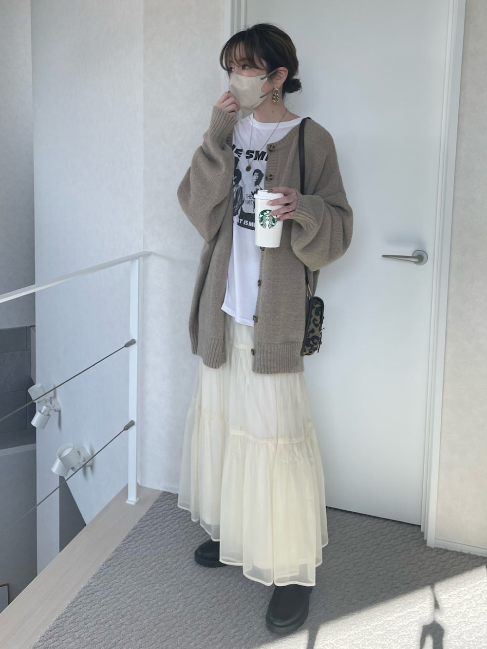 ベージュ系のカーディガン/ボレロ、ホワイト系のスカート、ブラウン系のショルダーバッグを着用したレディースの冬コーディネートの2枚目の写真