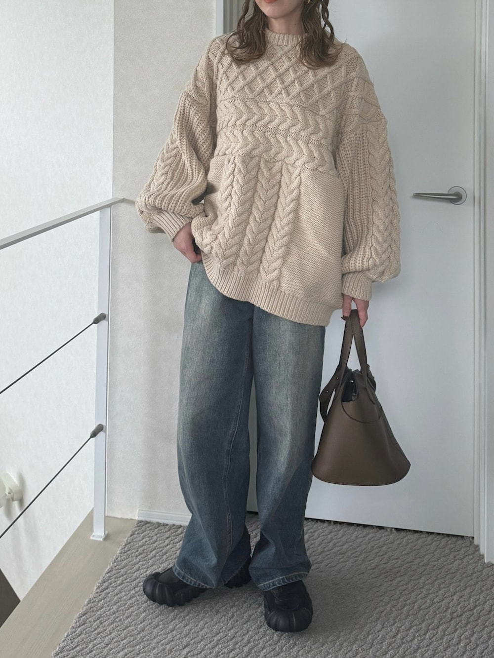 ベージュ系のニット/セーター、ブルー系のデニムパンツ、ブラック系のスニーカーを着用したレディースの冬コーディネートの2枚目の写真