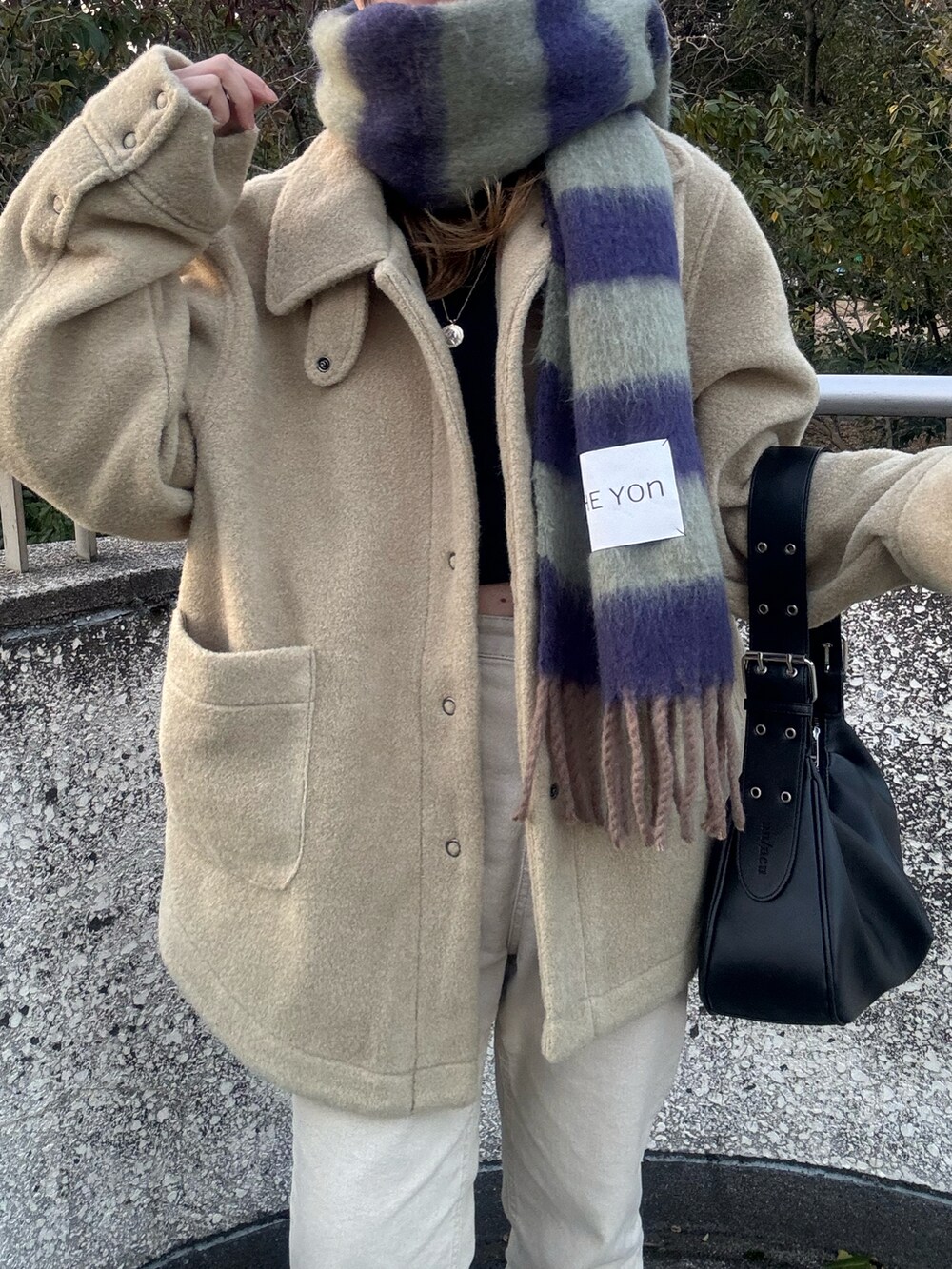 ブラック系のハンドバッグ、グリーン系のその他アウター、グリーン系のマフラーを着用したレディースの冬コーディネートの5枚目の写真