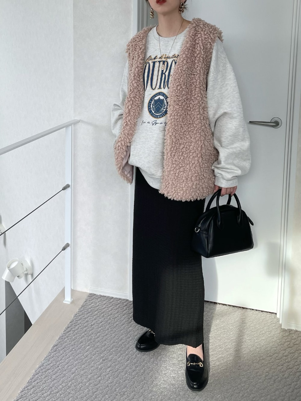 ベージュ系のベスト、ブラック系のスカート、ベージュ系のスウェットを着用したレディースの冬コーディネートの2枚目の写真