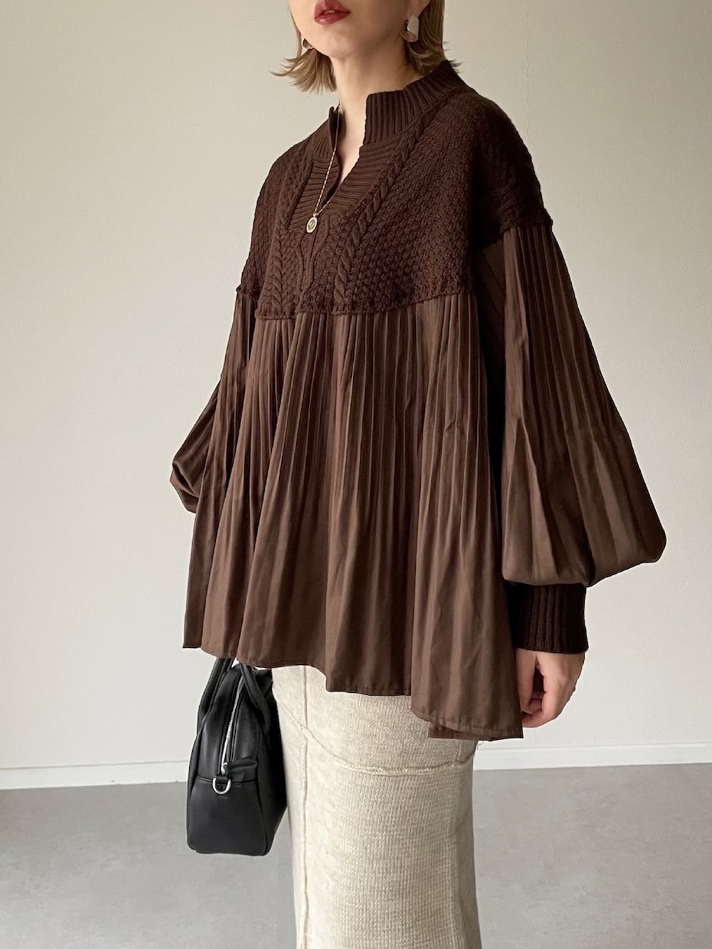 ブラウン系のニット/セーター、ベージュ系のスカート、ブラック系のボストンバッグを着用したレディースの秋コーディネートの3枚目の写真