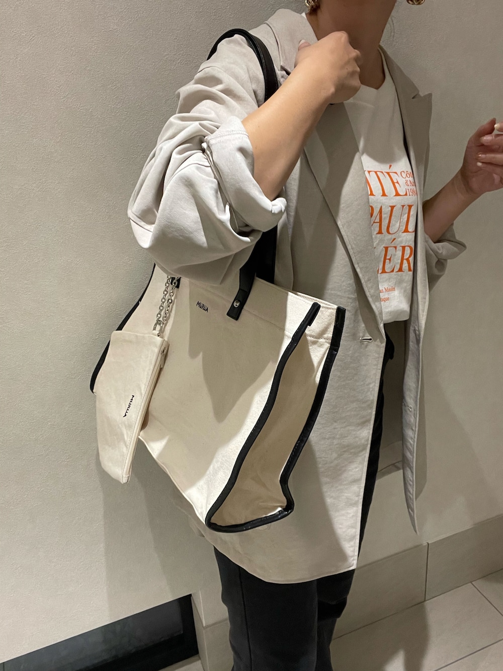 ホワイト系のトートバッグ、グレー系のテーラードジャケット、オレンジ系のTシャツ/カットソーを着用したレディースの秋コーディネートの3枚目の写真