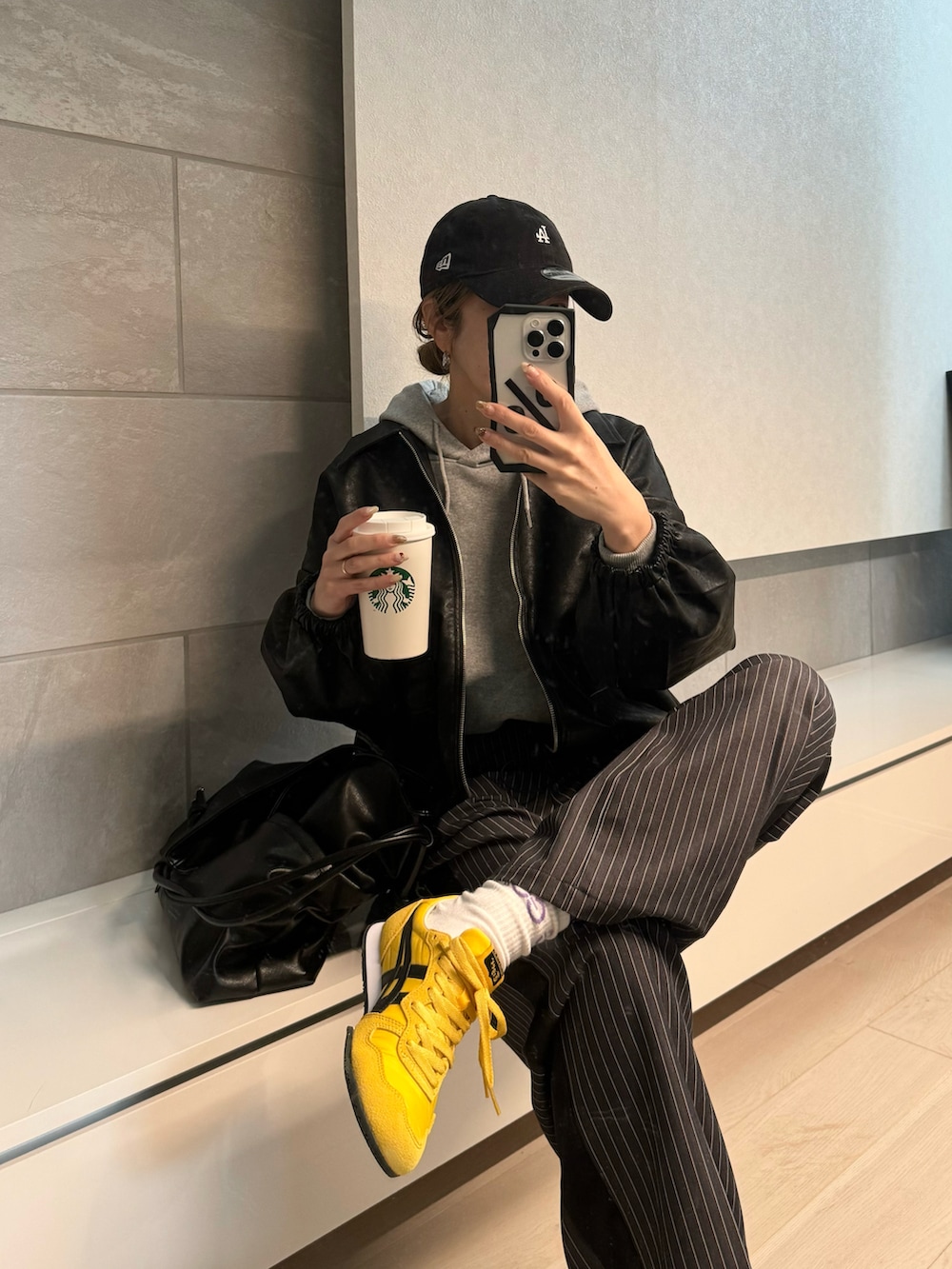 ブラック系のブルゾン、グレー系のスラックス、イエロー系のスニーカーを着用したレディースの秋コーディネートの4枚目の写真