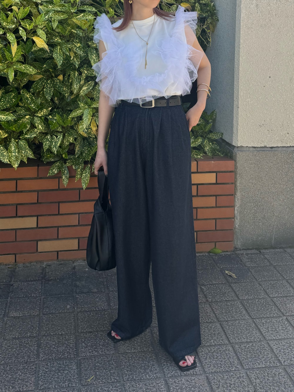 ブルー系のデニムパンツ、ホワイト系のタンクトップ、ブラック系のハンドバッグを着用したレディースの春コーディネートの2枚目の写真