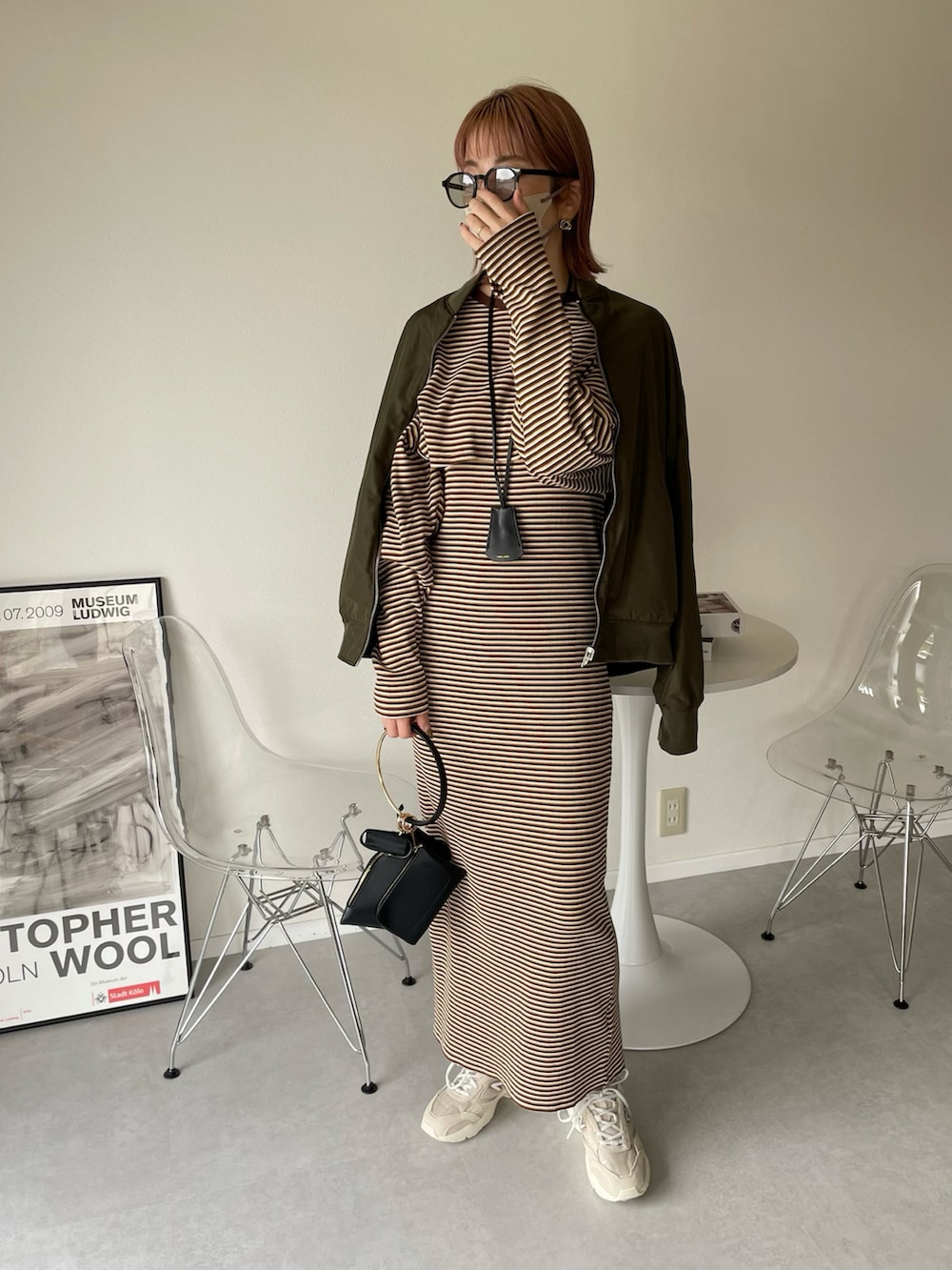 ブラウン系のワンピース、ブラック系のハンドバッグ、グリーン系のMA-1を着用したレディースの春コーディネートの3枚目の写真