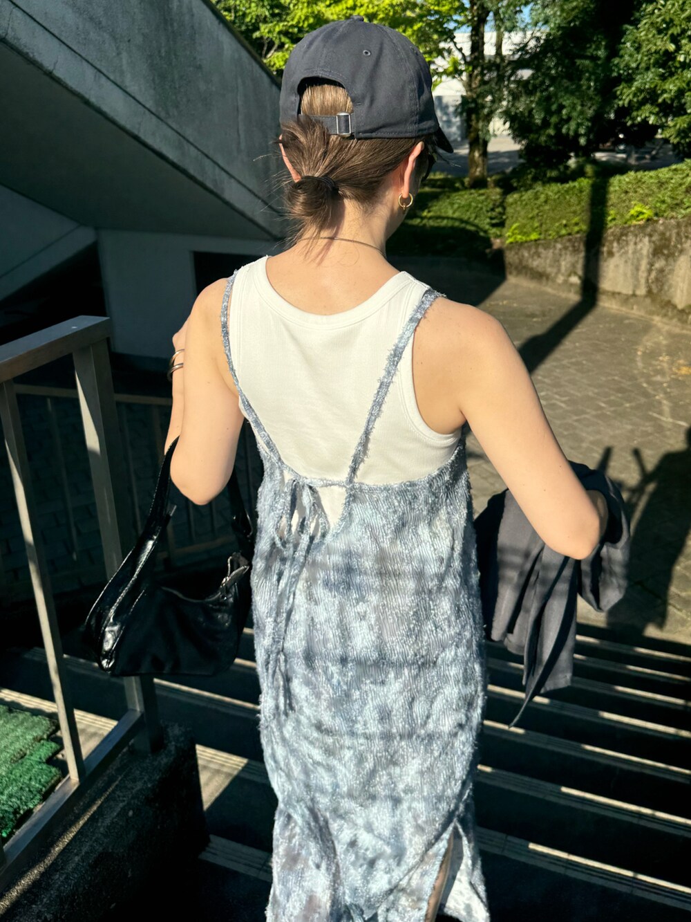 グレー系のワンピース、ブラック系のスニーカー、ブラック系のショルダーバッグを着用したレディースの夏コーディネートの5枚目の写真