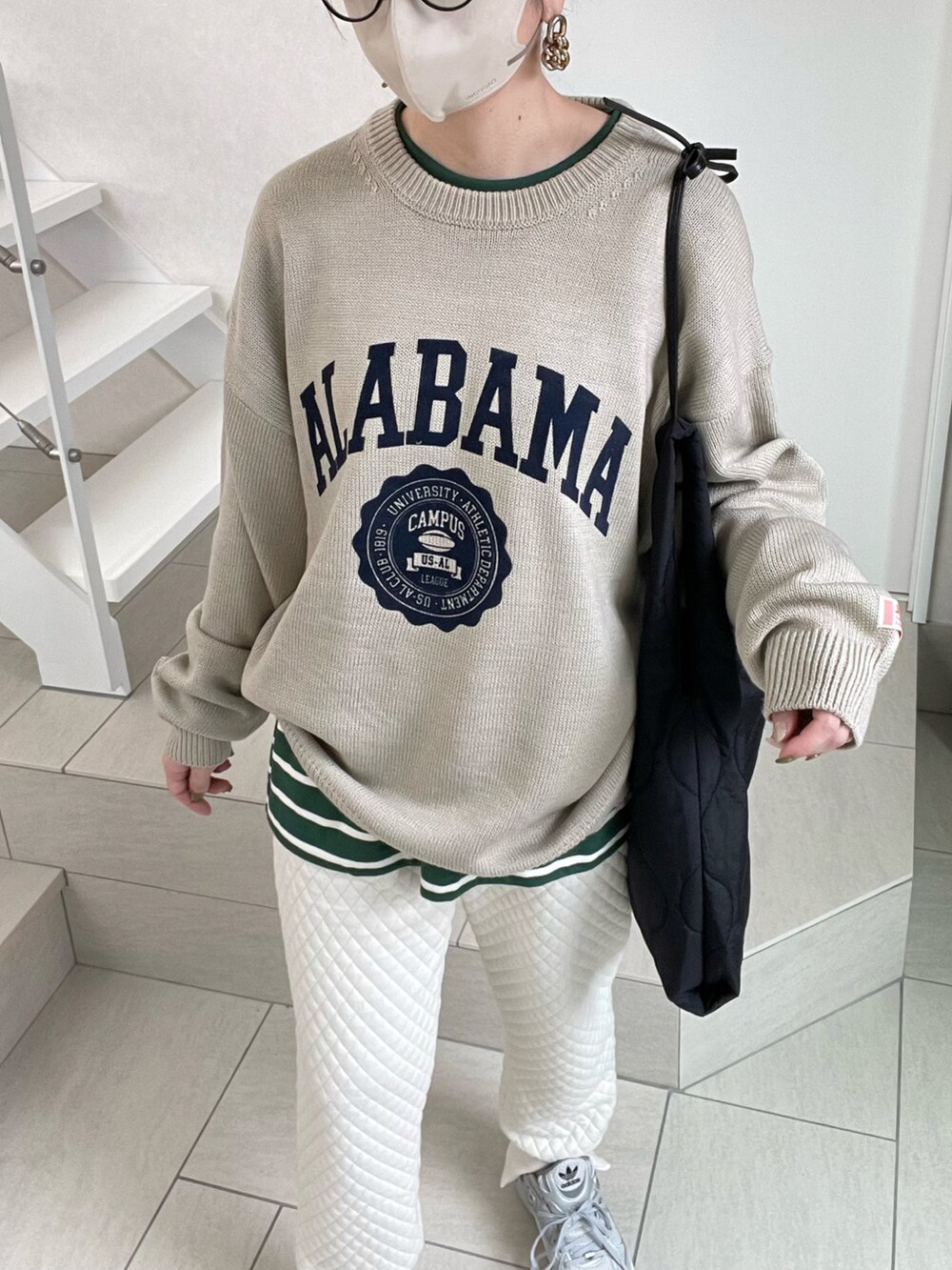 ベージュ系のニット/セーター、ホワイト系のスウェットパンツ、ブラック系のショルダーバッグを着用したレディースの冬コーディネートの2枚目の写真