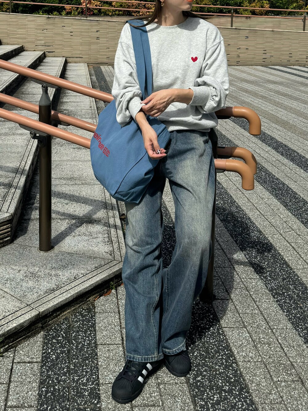 グレー系のスウェット、ブルー系のトートバッグ、ブルー系のデニムパンツを着用したレディースの秋コーディネートの4枚目の写真