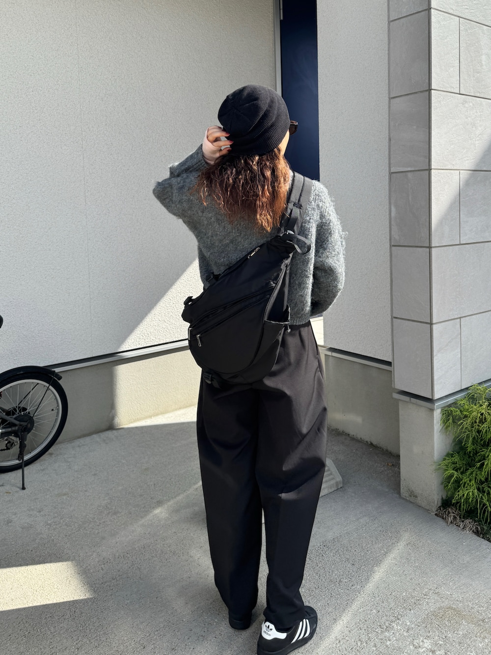 グレー系のニット/セーター、ブラック系のその他パンツ、ブラック系のボディバッグ/ウエストポーチを着用したレディースの秋コーディネートの3枚目の写真