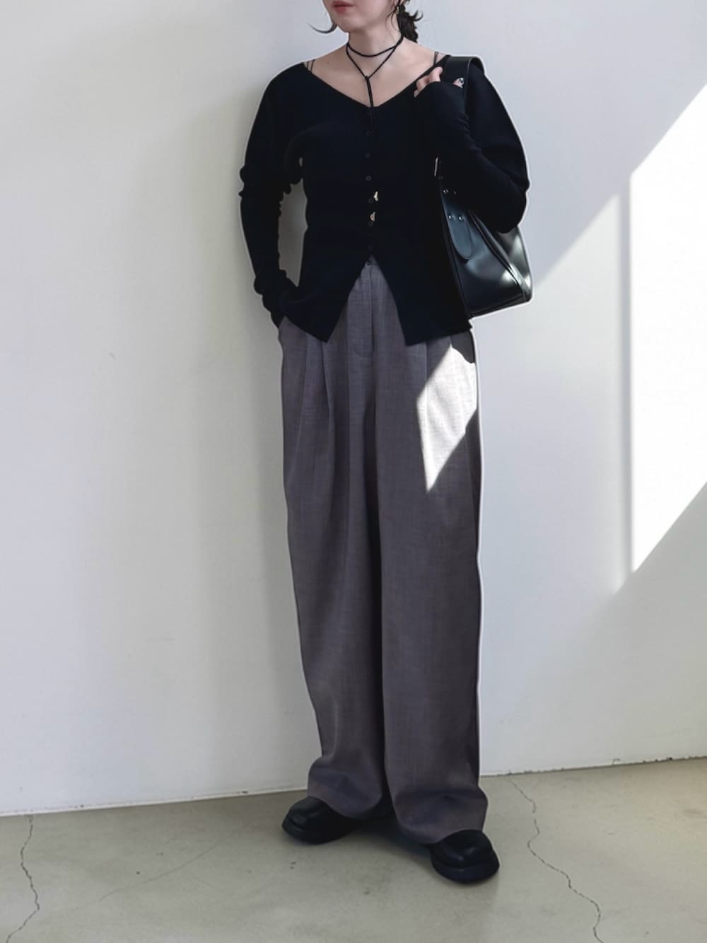 グレー系のスラックス、ブラック系のハンドバッグ、ブラック系のその他シューズを着用したレディースの春コーディネートの3枚目の写真