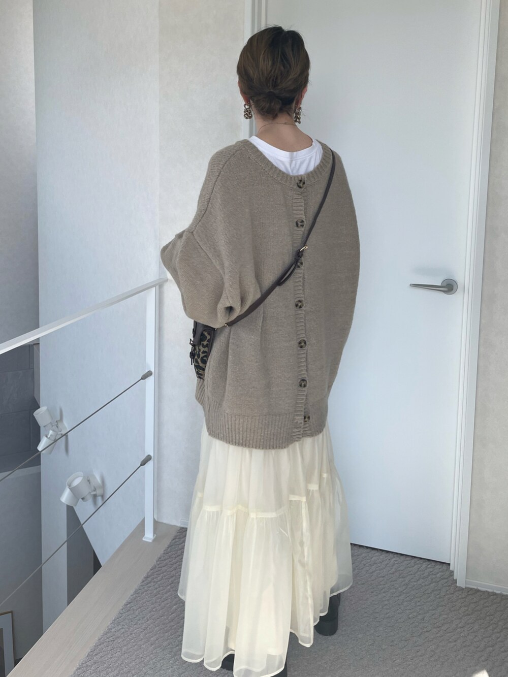 ベージュ系のカーディガン/ボレロ、ホワイト系のスカート、ブラウン系のショルダーバッグを着用したレディースの冬コーディネートの5枚目の写真