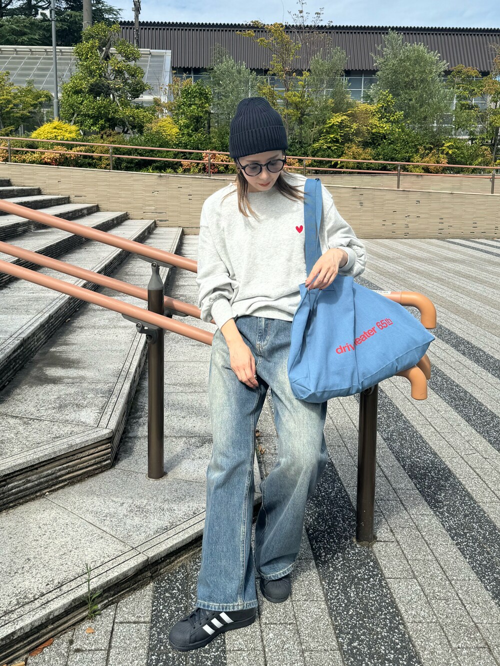 グレー系のスウェット、ブルー系のトートバッグ、ブルー系のデニムパンツを着用したレディースの秋コーディネートの3枚目の写真
