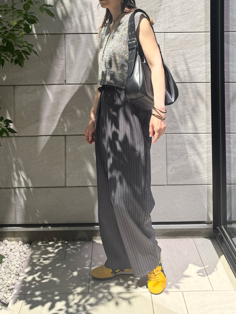 ブラック系のベスト、グレー系のスラックス、ブラック系のハンドバッグを着用したレディースの夏コーディネートの4枚目の写真