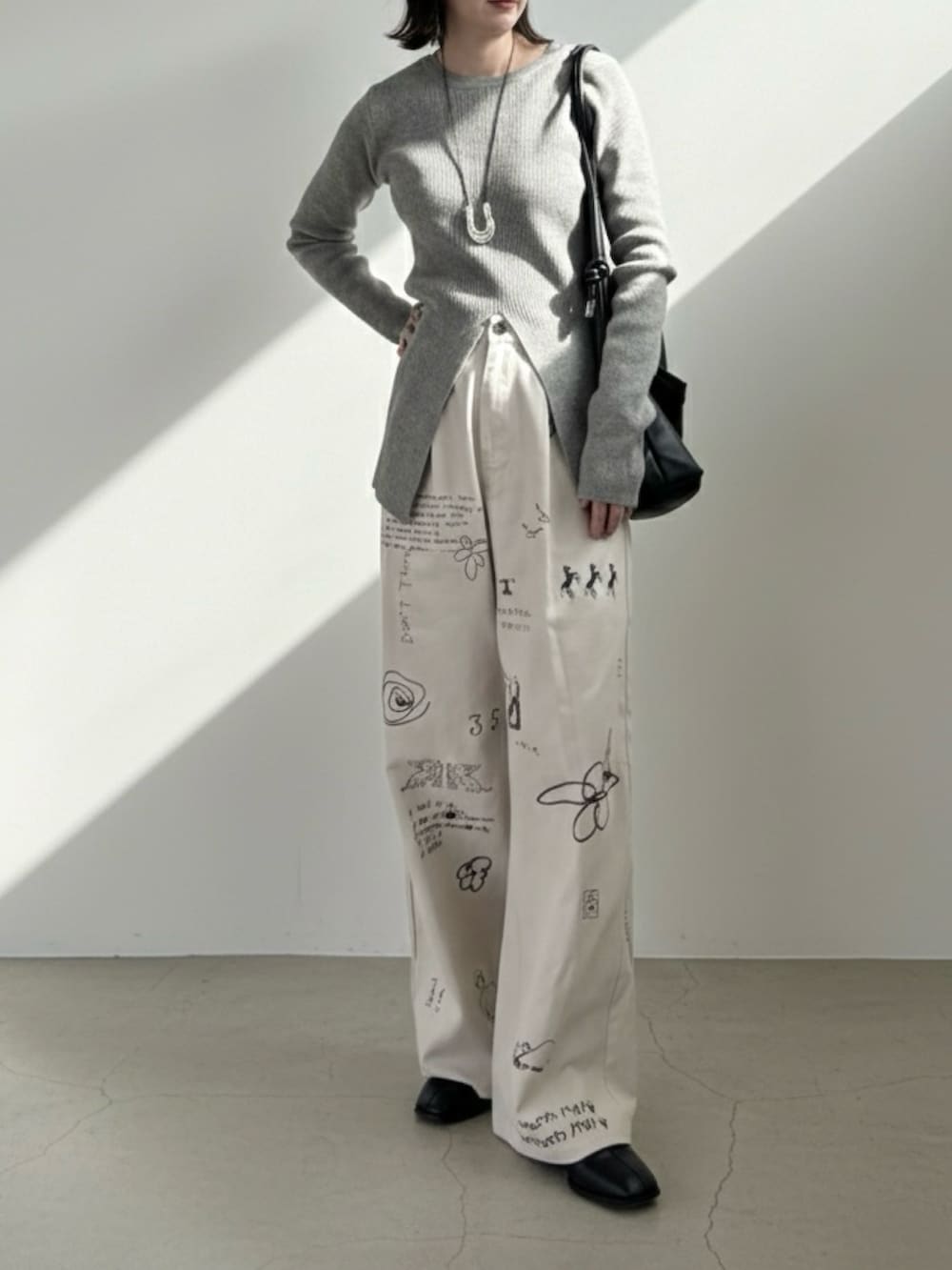 グレー系のニット/セーター、ホワイト系のその他パンツ、ブラック系のショルダーバッグを着用したレディースの冬コーディネートの2枚目の写真