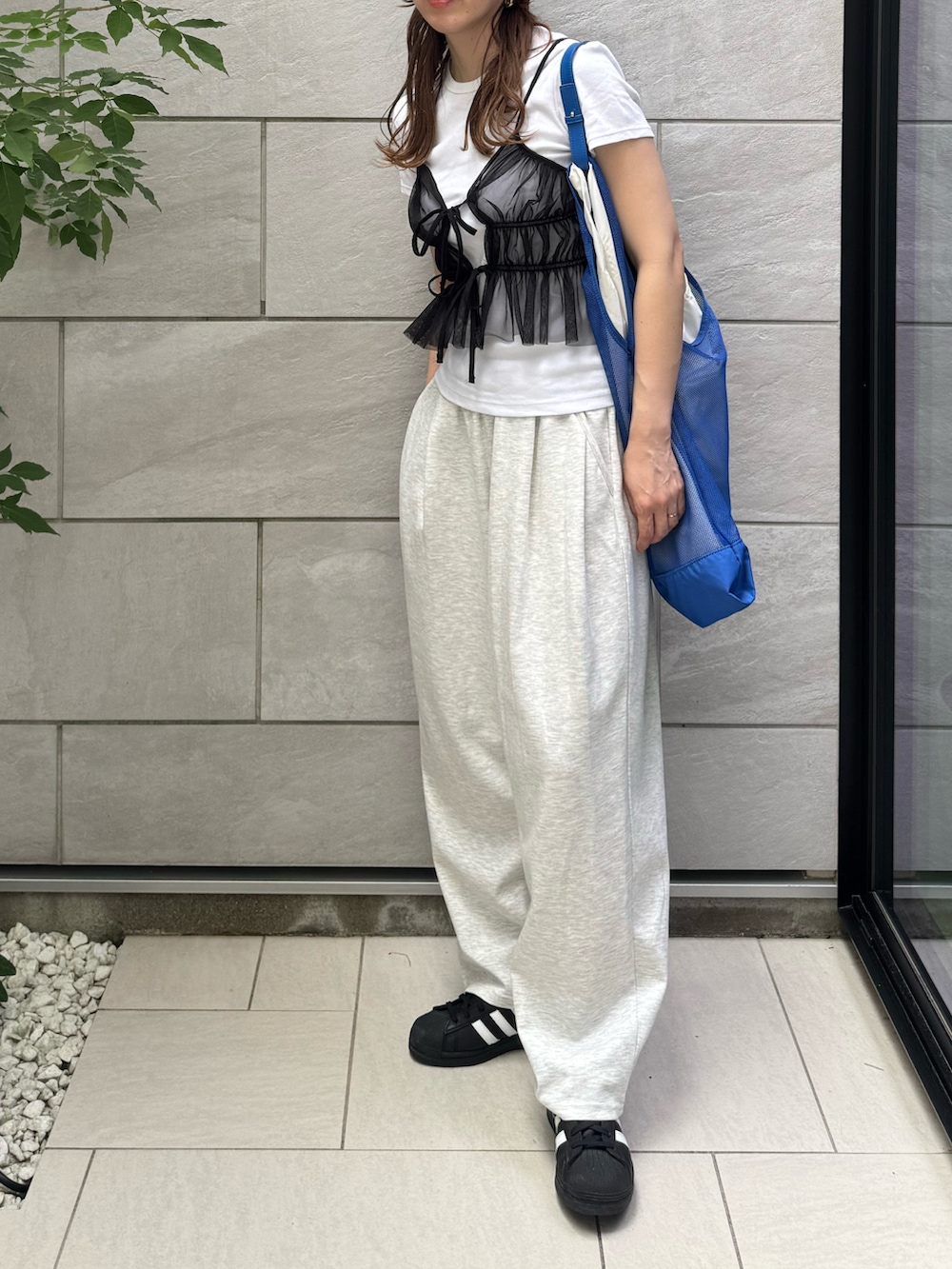 ブラック系のスニーカー、グレー系のデニムパンツ、ブルー系のトートバッグを着用したレディースの夏コーディネートの2枚目の写真