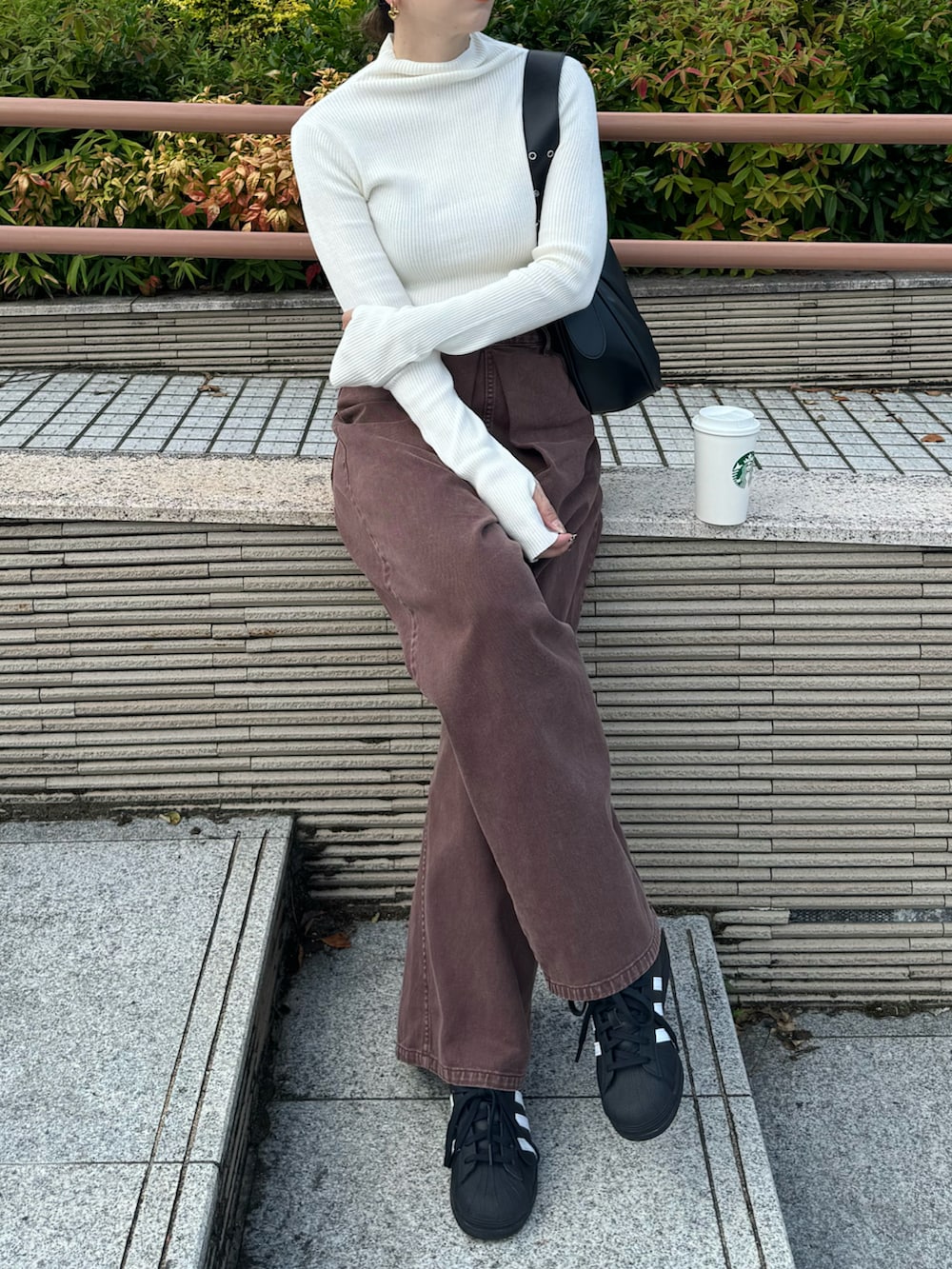 ホワイト系のニット/セーター、ブラウン系のデニムパンツ、ブラック系のスニーカーを着用したレディースの秋コーディネートの3枚目の写真