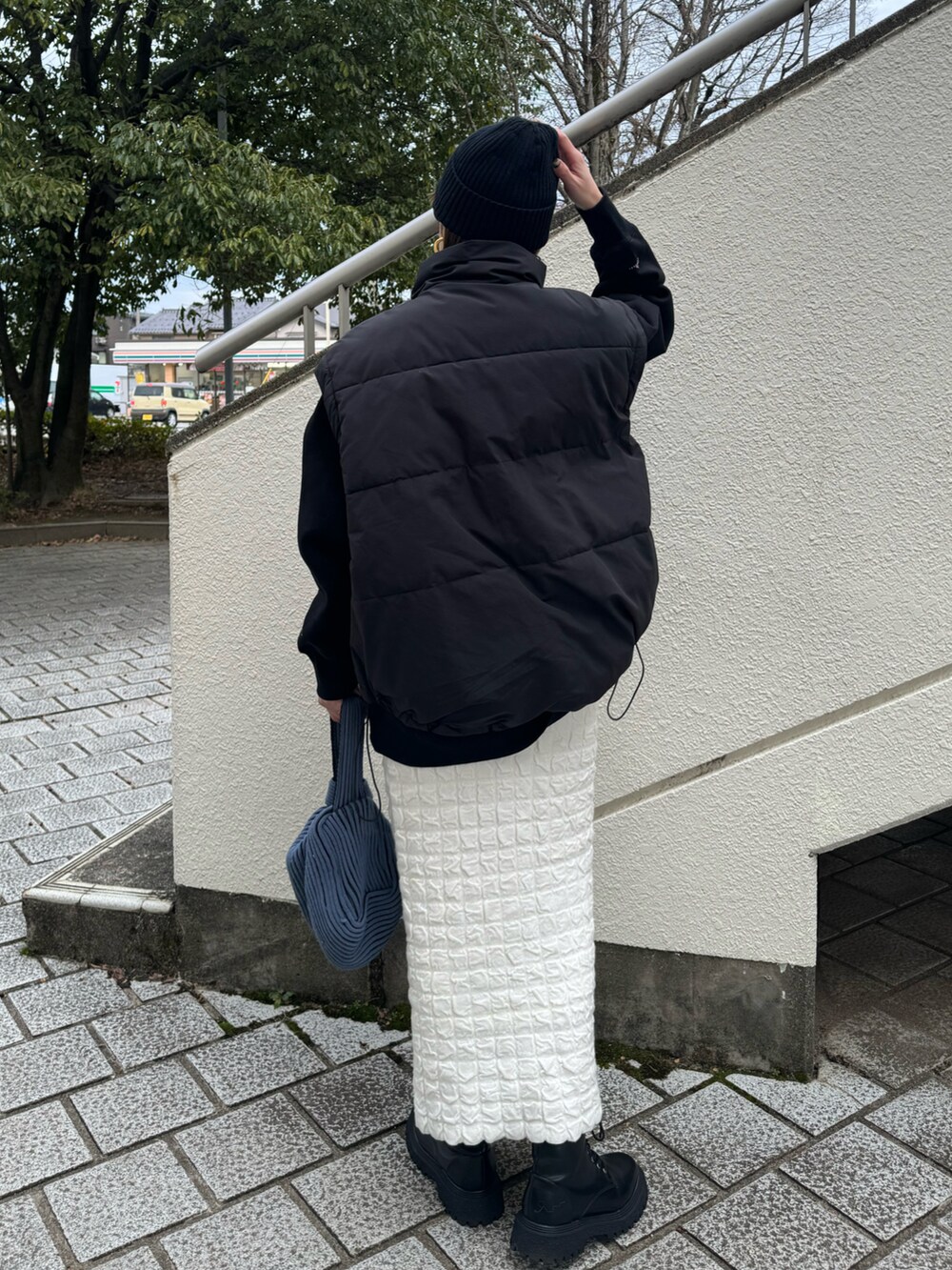 ブラック系のスウェット、ブラック系のブーツ、ブルー系のハンドバッグを着用したレディースの冬コーディネートの5枚目の写真