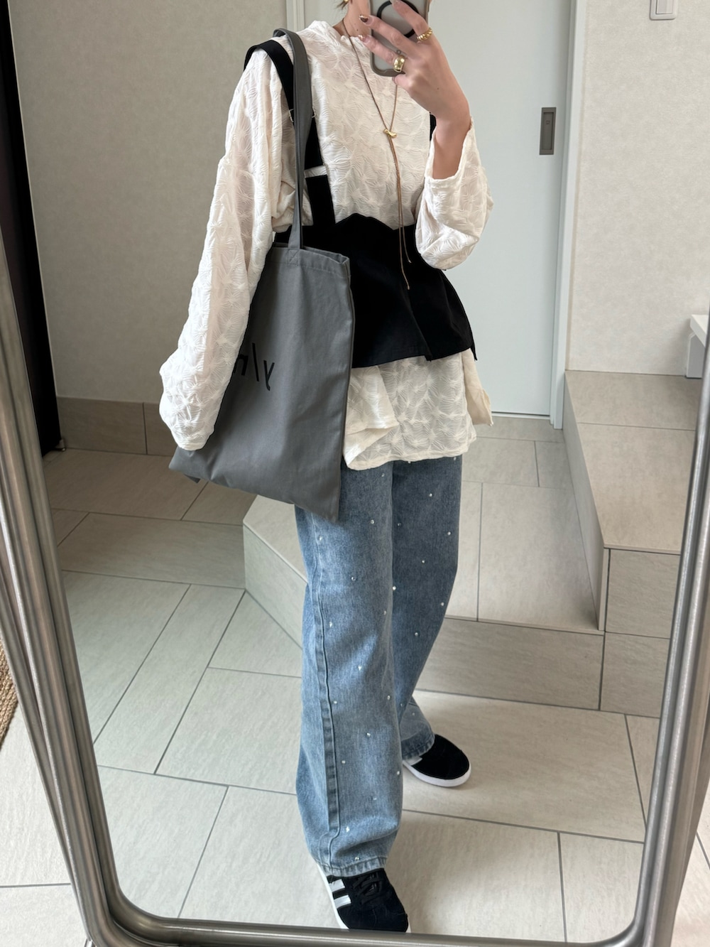 ホワイト系のTシャツ/カットソー、グレー系のトートバッグ、ブルー系のデニムパンツを着用したレディースの冬コーディネートの4枚目の写真