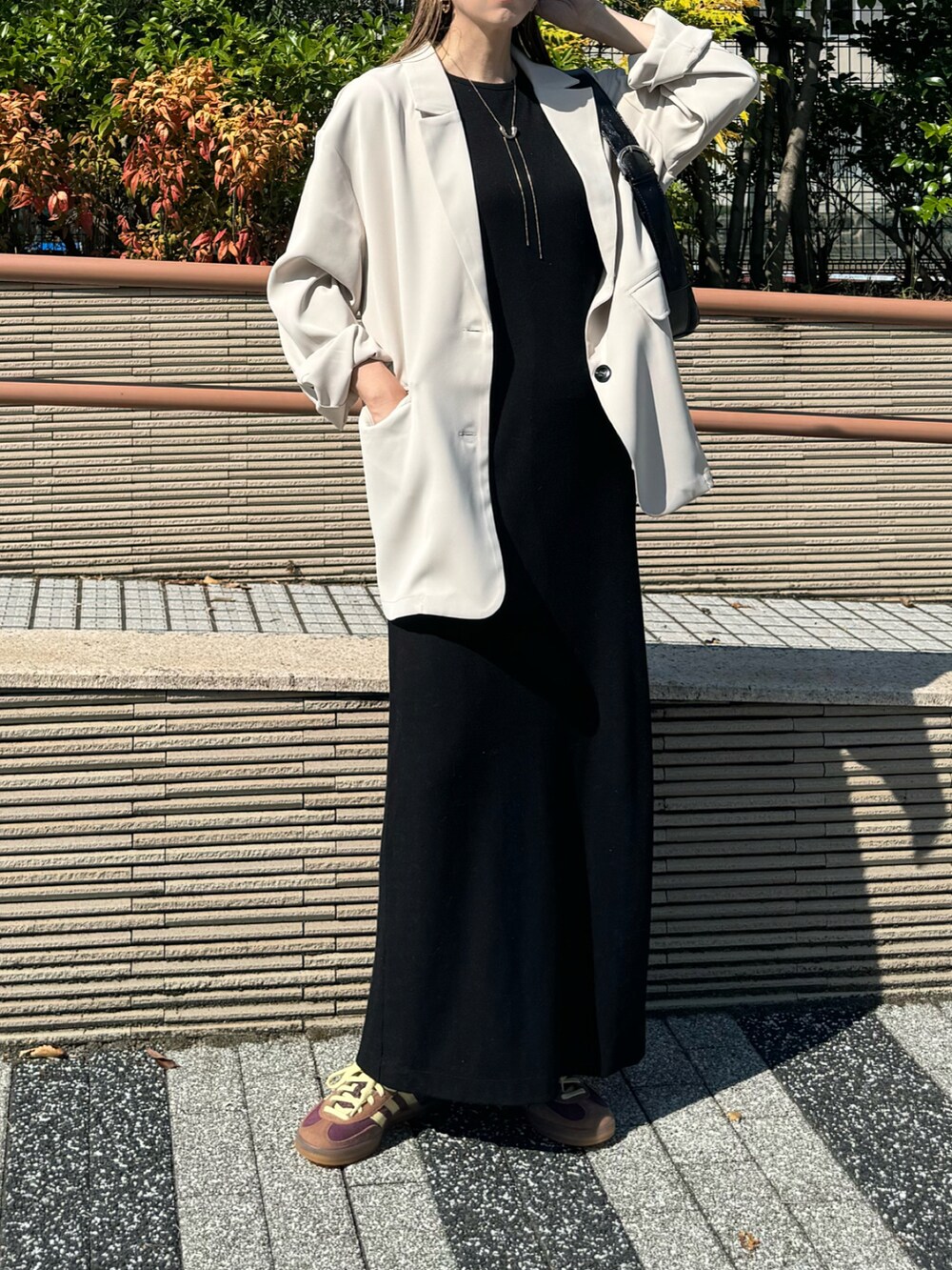 ホワイト系のテーラードジャケット、レッド系のスニーカー、ブラック系のワンピースを着用したレディースの秋コーディネートの3枚目の写真