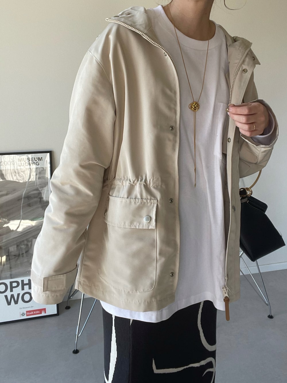 ホワイト系のマウンテンパーカー、グレー系のスカート、ブラック系のハンドバッグを着用したレディースの春コーディネートの5枚目の写真