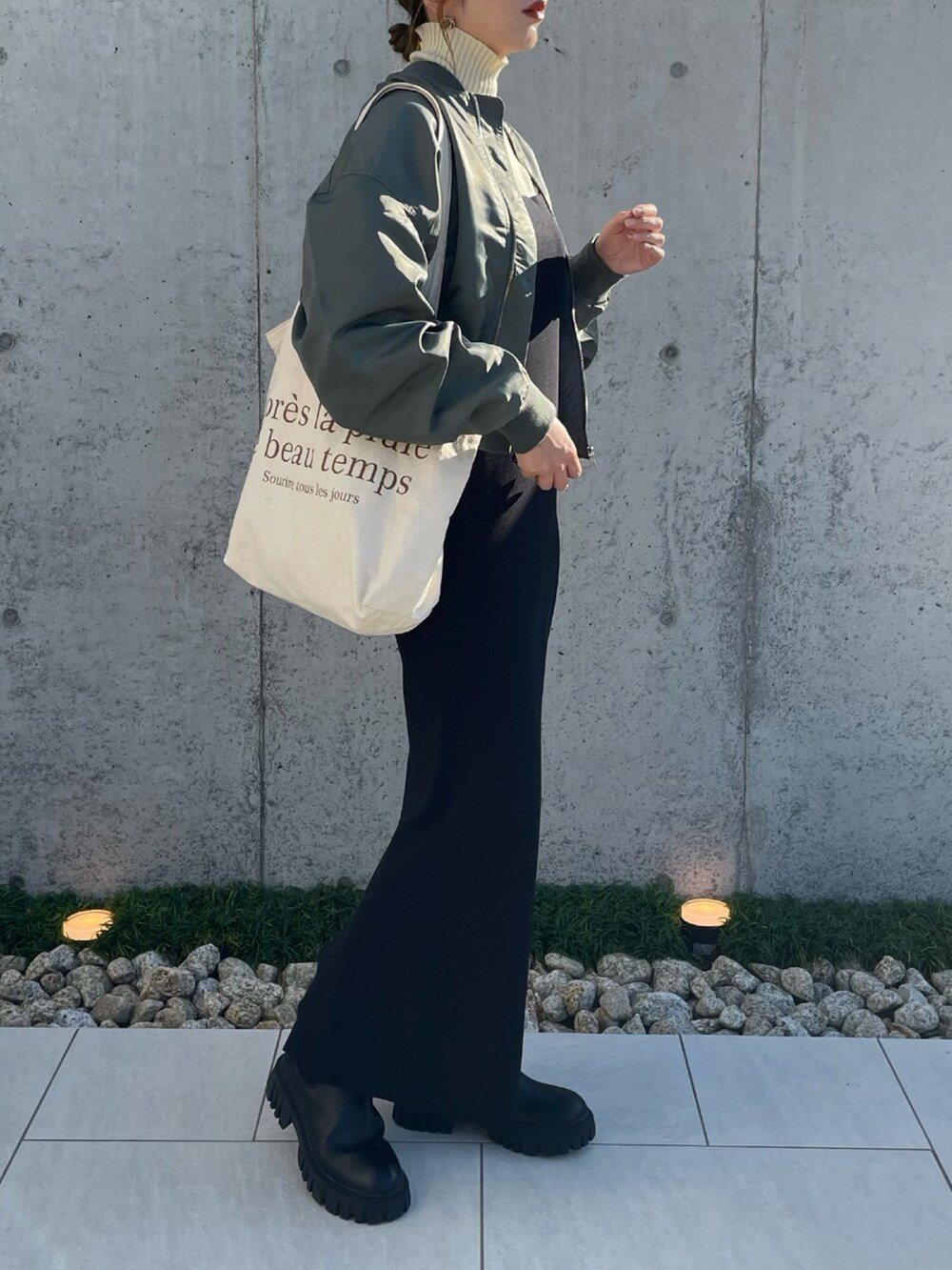 グリーン系のブルゾン、ホワイト系のニット/セーター、ブラック系のブーツを着用したレディースの秋コーディネートの2枚目の写真