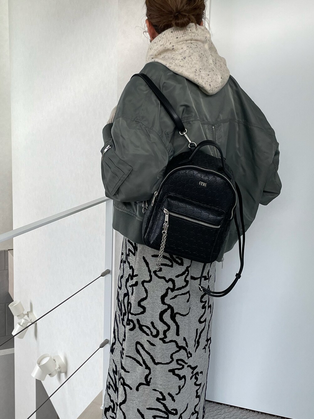 ブラック系のバックパック/リュック、ホワイト系のワンピース、グリーン系のブルゾンを着用したレディースの冬コーディネートの3枚目の写真