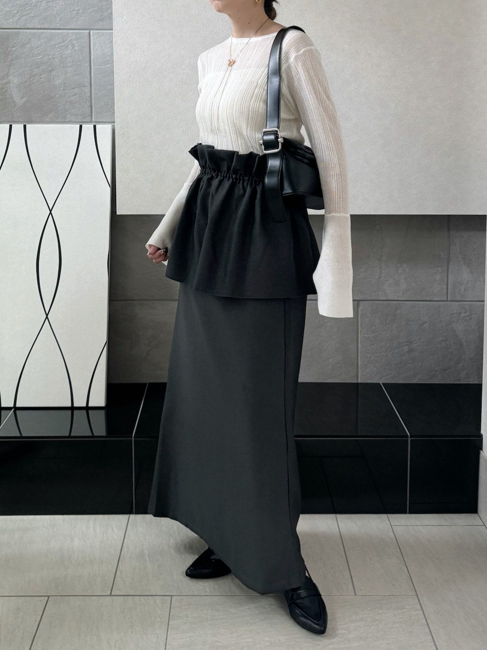 グレー系のスカート、ホワイト系のニット/セーター、ブラック系のローファーを着用したレディースの秋コーディネートの3枚目の写真