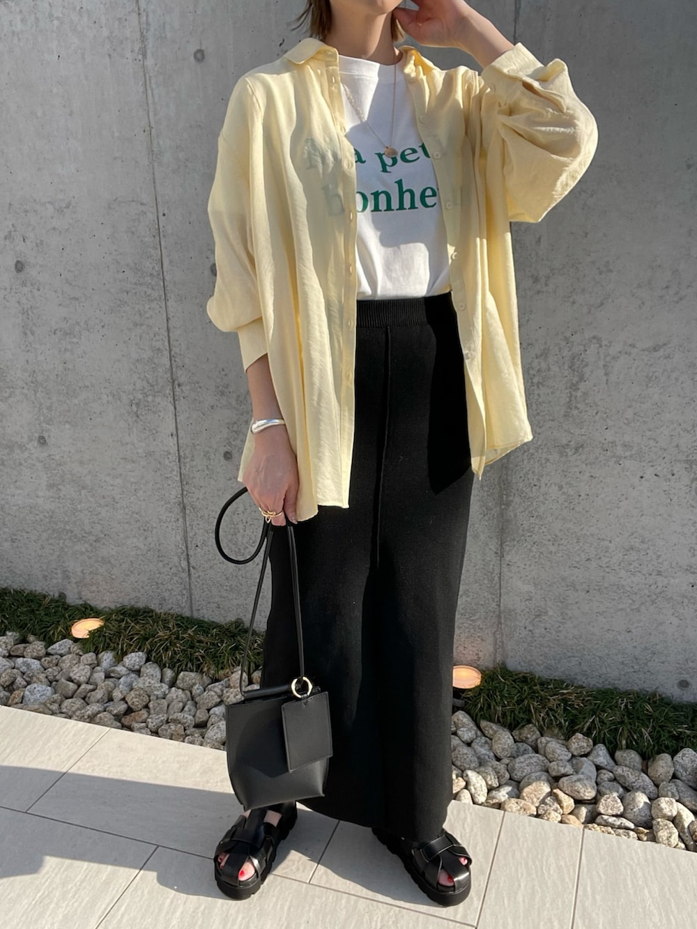 イエロー系のシャツ/ブラウス、ブラック系のサンダル、ブラック系のショルダーバッグを着用したレディースの春コーディネートの2枚目の写真