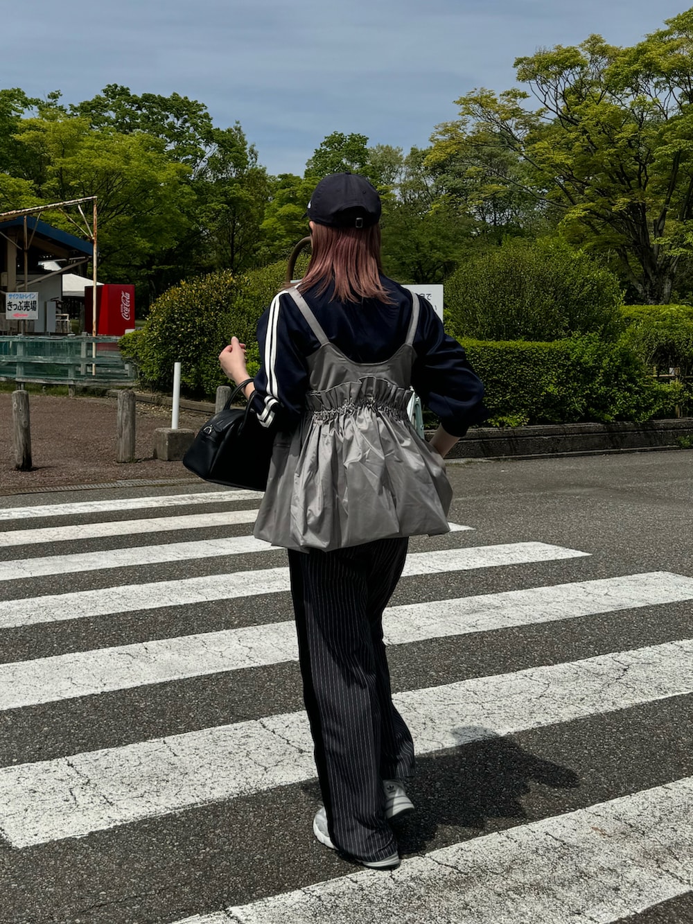グレー系のスラックス、グレー系のスニーカー、ブラック系のショルダーバッグを着用したレディースの春コーディネートの4枚目の写真