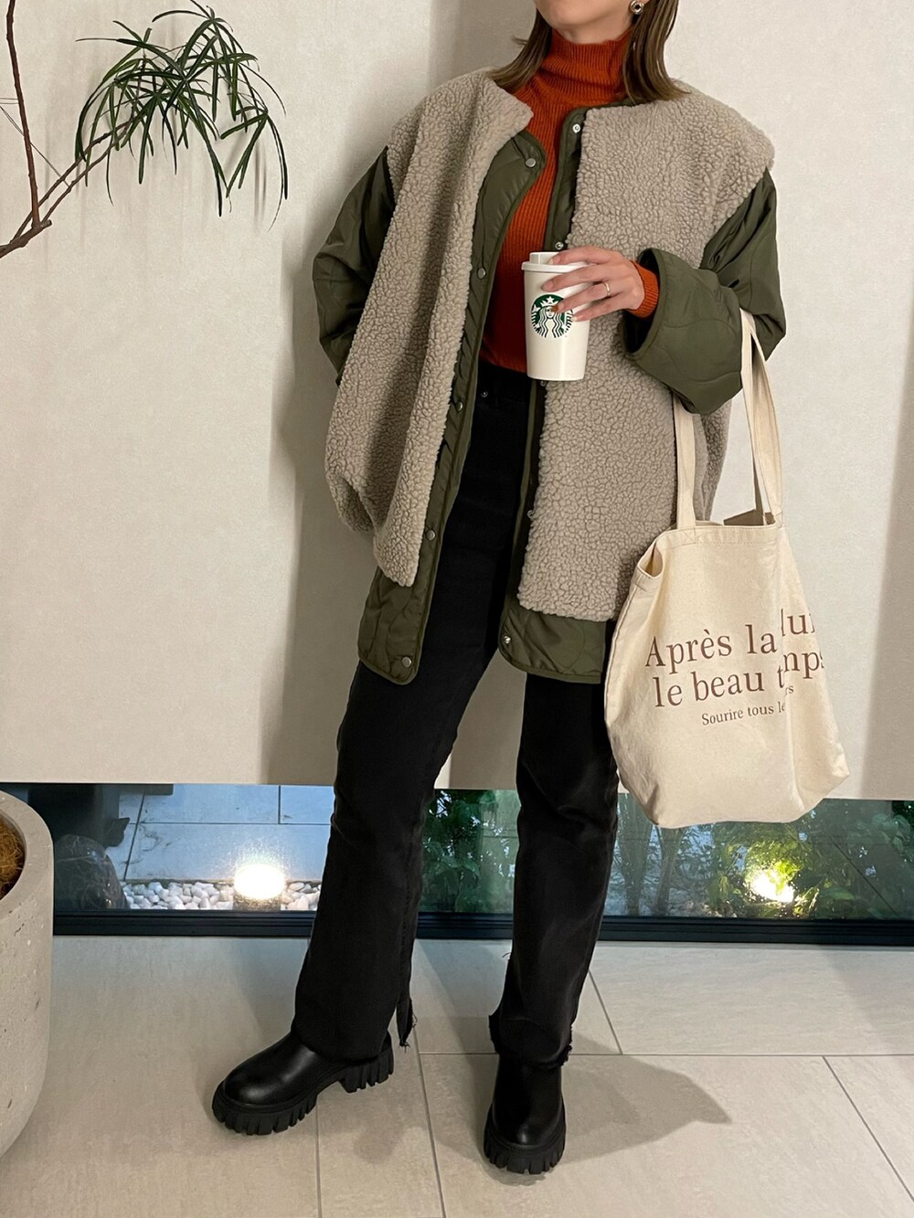 グリーン系のその他アウター、オレンジ系のニット/セーター、ブラック系のデニムパンツを着用したレディースの秋コーディネートの3枚目の写真