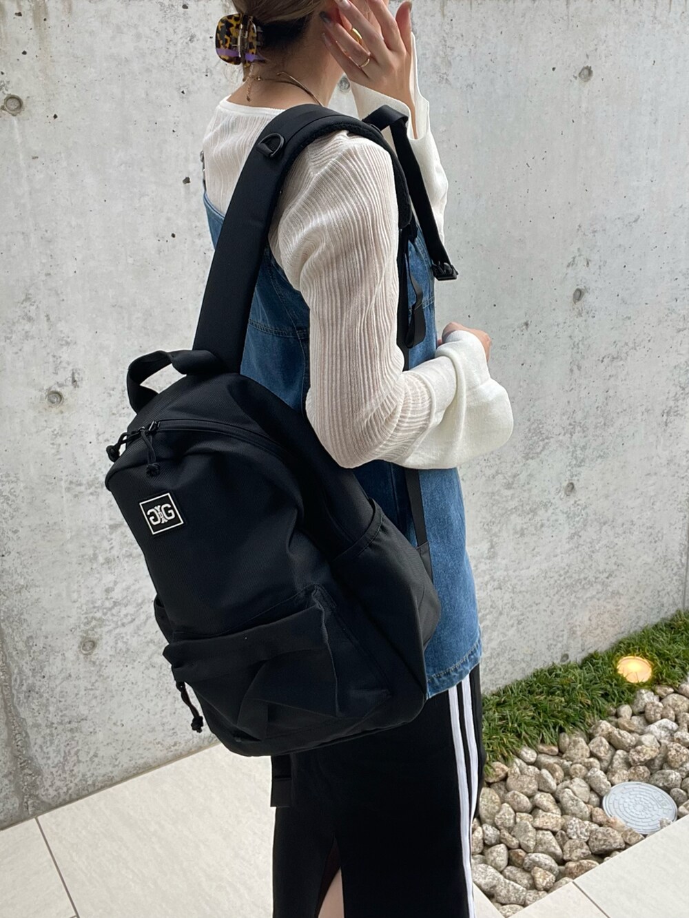 ブラック系のバックパック/リュック、ホワイト系のニット/セーター、グレー系のスニーカーを着用したレディースの秋コーディネートの3枚目の写真