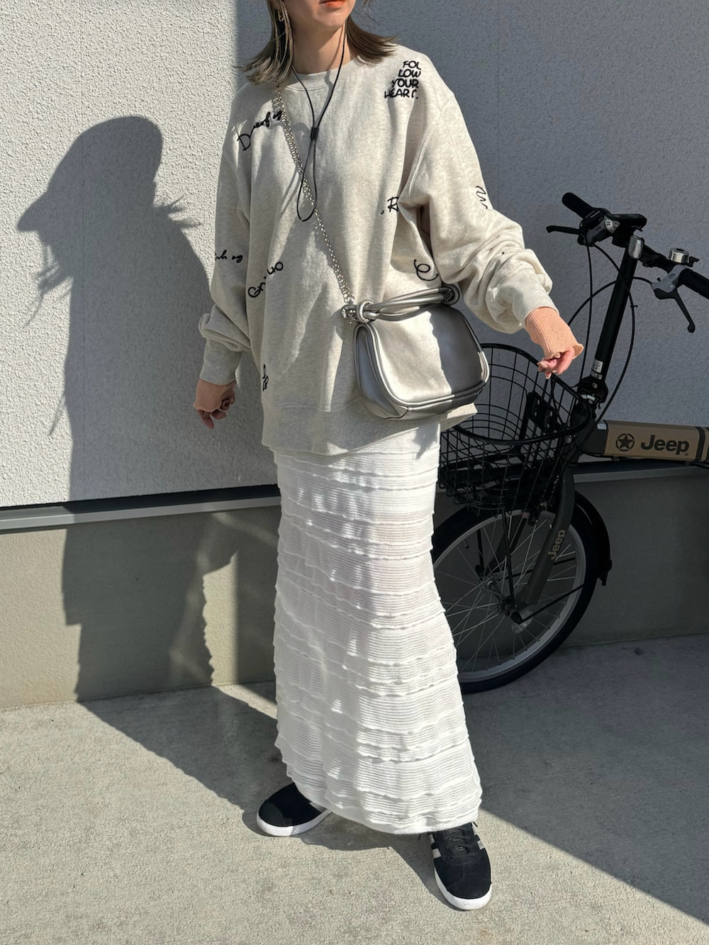 ホワイト系のスウェット、ホワイト系のスカート、ブラック系のスニーカーを着用したレディースの春コーディネートの3枚目の写真