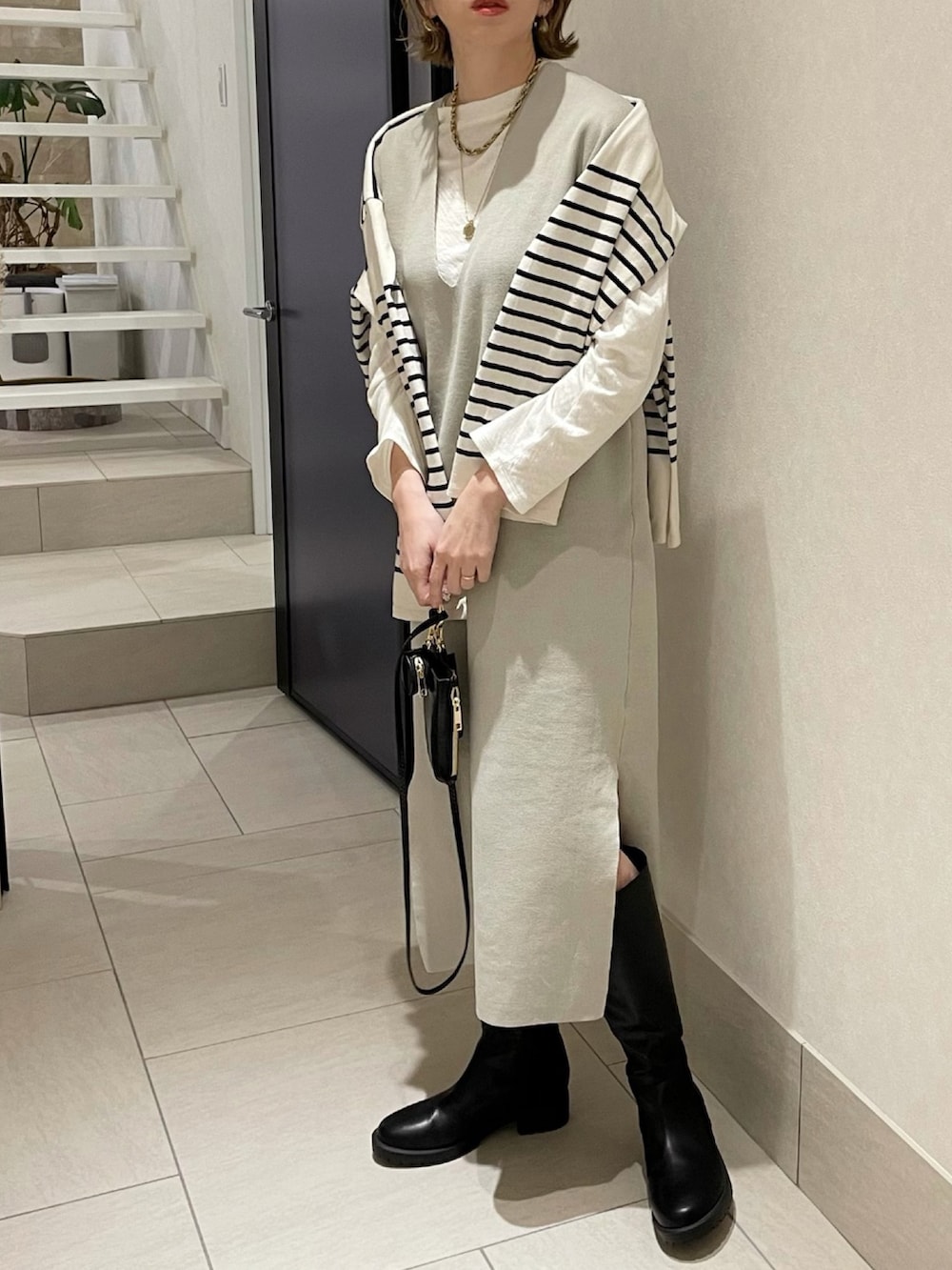 ベージュ系のワンピース、ブラック系のショルダーバッグ、ブラック系のブーツを着用したレディースの冬コーディネートの3枚目の写真