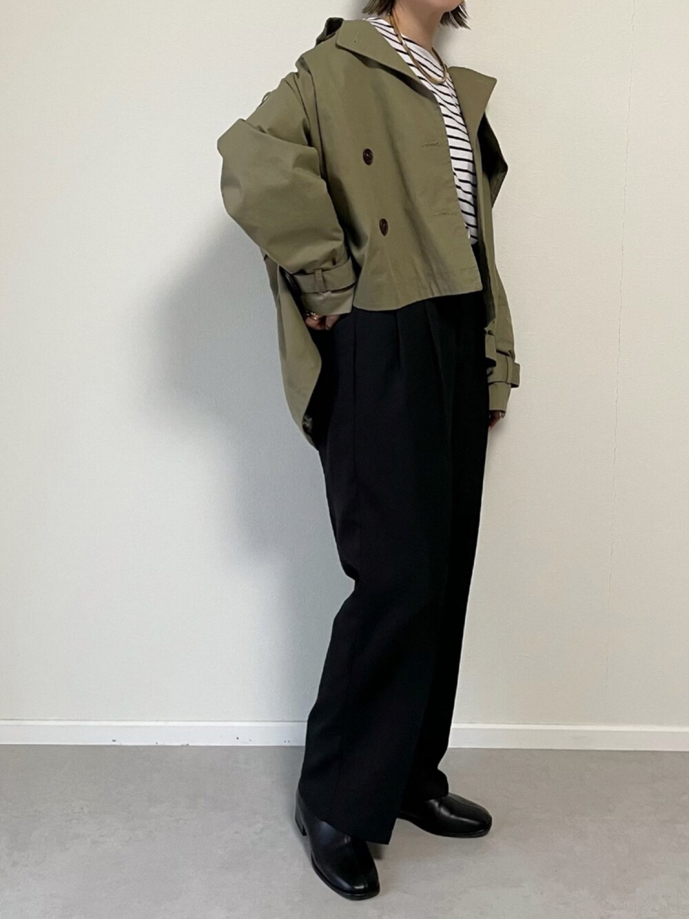 ブラック系のショルダーバッグ、グリーン系のトレンチコート、ブラック系のその他シューズを着用したレディースの冬コーディネートの2枚目の写真