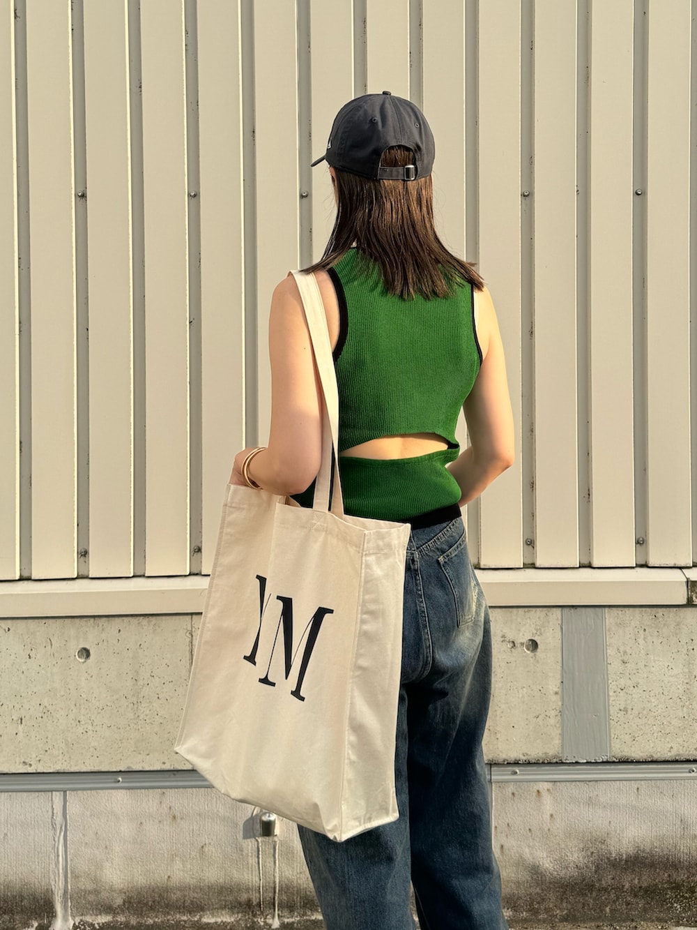 グリーン系のタンクトップ、ブラック系のスニーカー、ホワイト系のトートバッグを着用したレディースの夏コーディネートの4枚目の写真