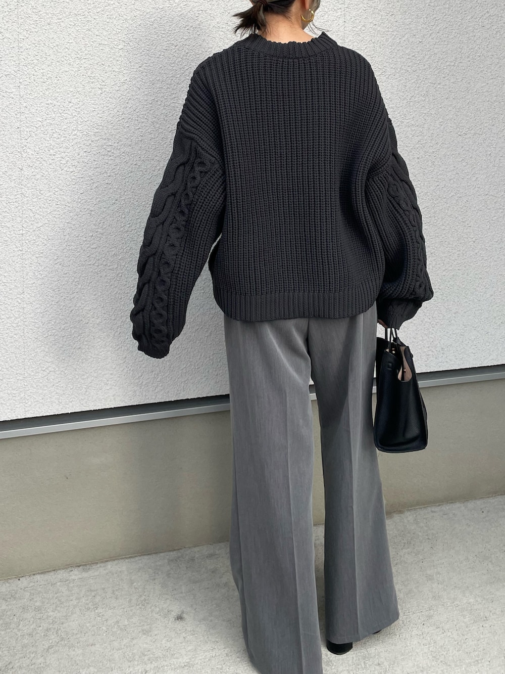 ブラック系のニット/セーター、ブラック系のハンドバッグを着用したレディースの秋コーディネートの4枚目の写真