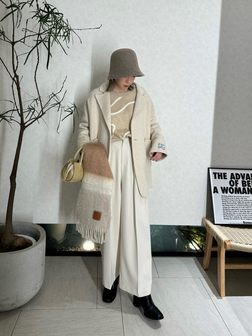 ベージュ系のニット/セーター、ホワイト系のその他パンツ、ベージュ系のハンドバッグを着用したレディースの冬コーディネートの2枚目の写真