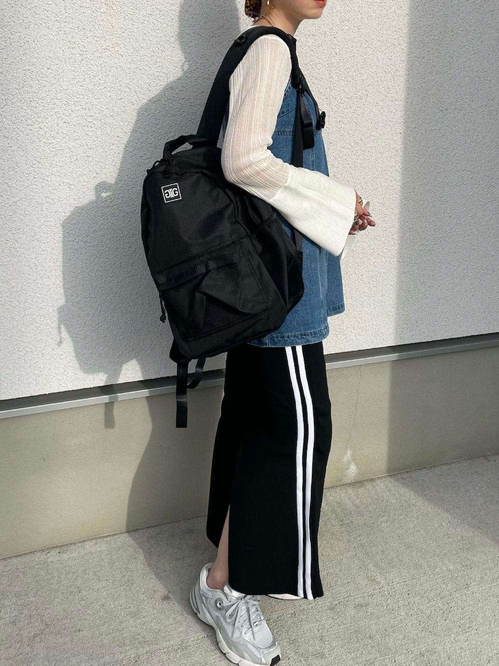 ブラック系のバックパック/リュック、ホワイト系のニット/セーター、グレー系のスニーカーを着用したレディースの秋コーディネートの2枚目の写真