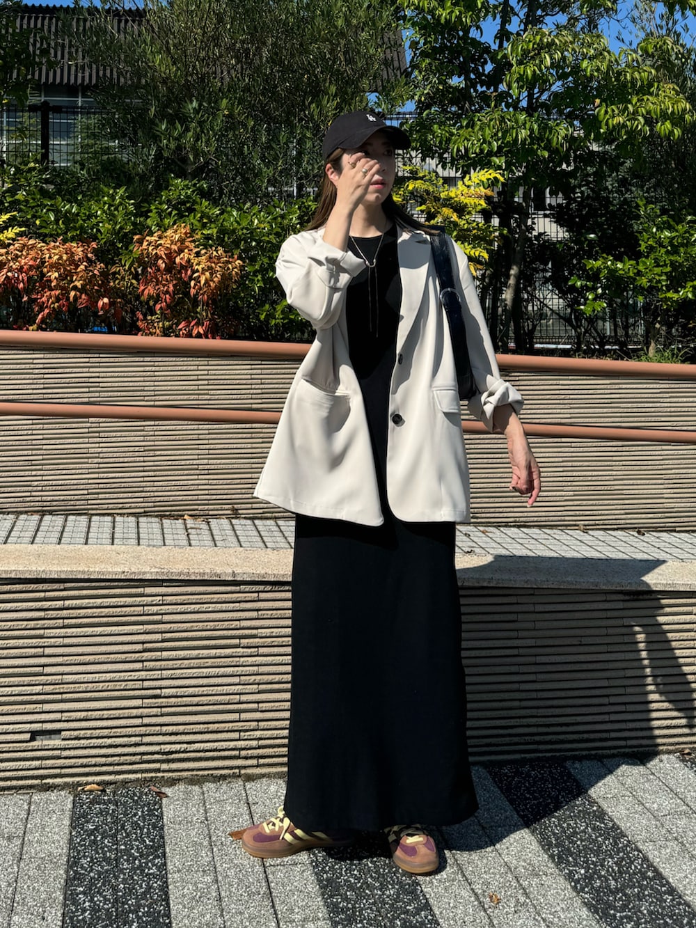 ホワイト系のテーラードジャケット、レッド系のスニーカー、ブラック系のワンピースを着用したレディースの秋コーディネートの2枚目の写真