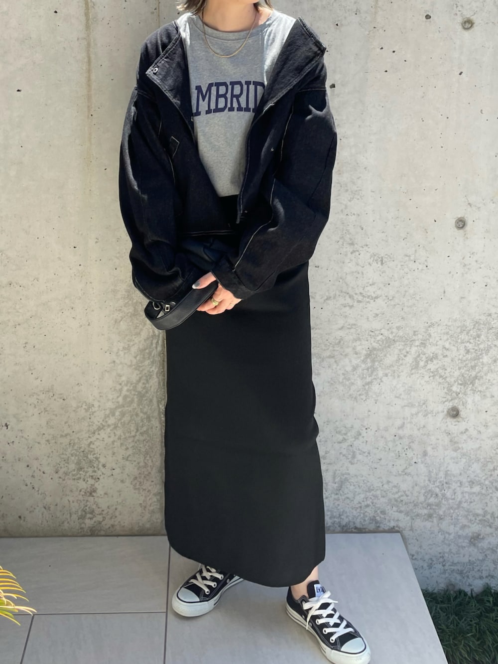 グレー系のTシャツ/カットソー、ブラック系のスカート、ブラック系のデニムジャケットを着用したレディースの秋コーディネートの4枚目の写真