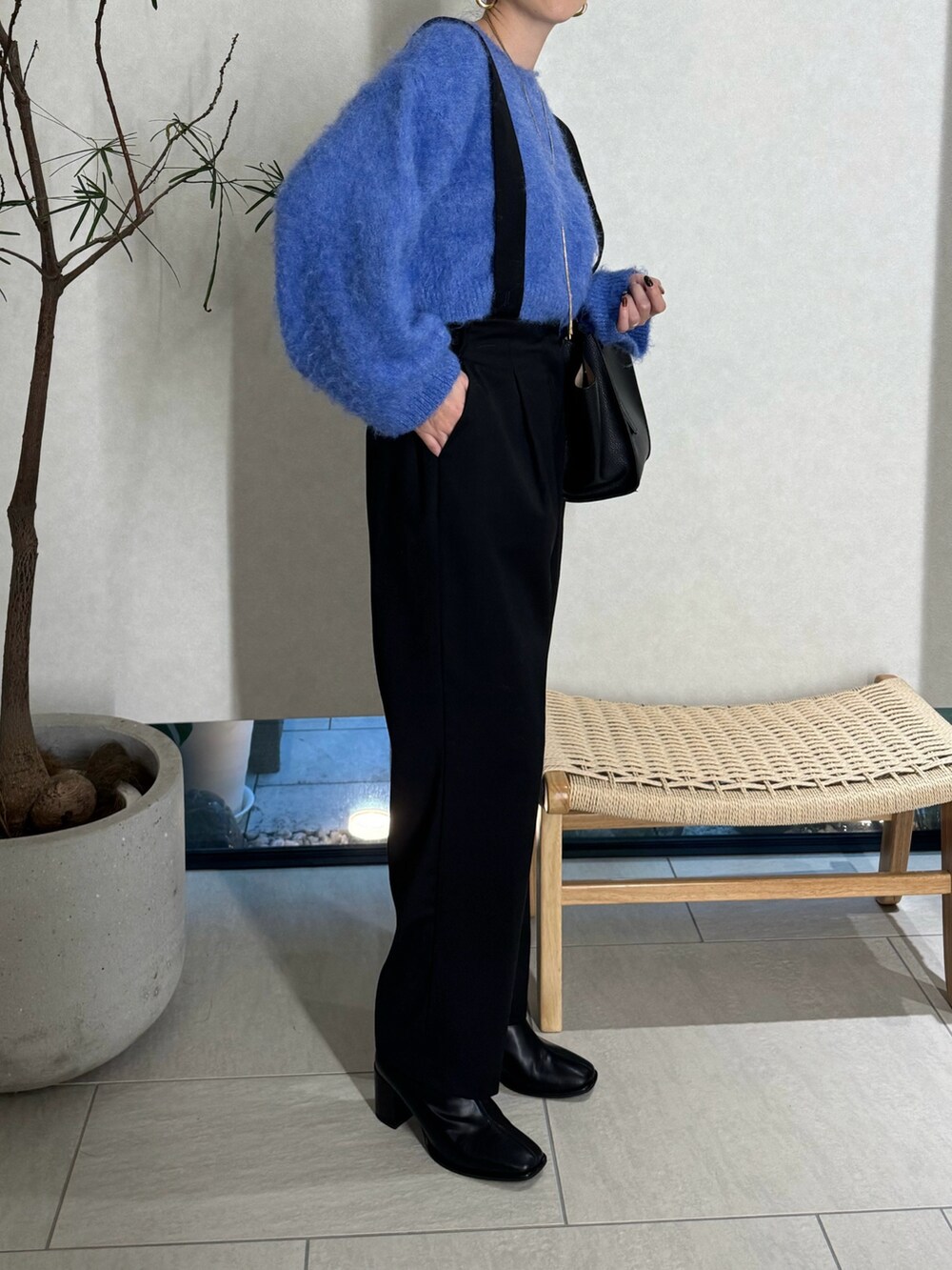 ブラック系のスラックス、ブルー系のニット/セーター、ブラック系のハンドバッグを着用したレディースの秋コーディネートの2枚目の写真