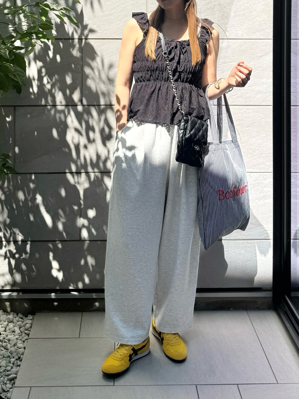 グレー系のデニムパンツ、ブラック系のトートバッグ、イエロー系のスニーカーを着用したレディースの秋コーディネートの3枚目の写真