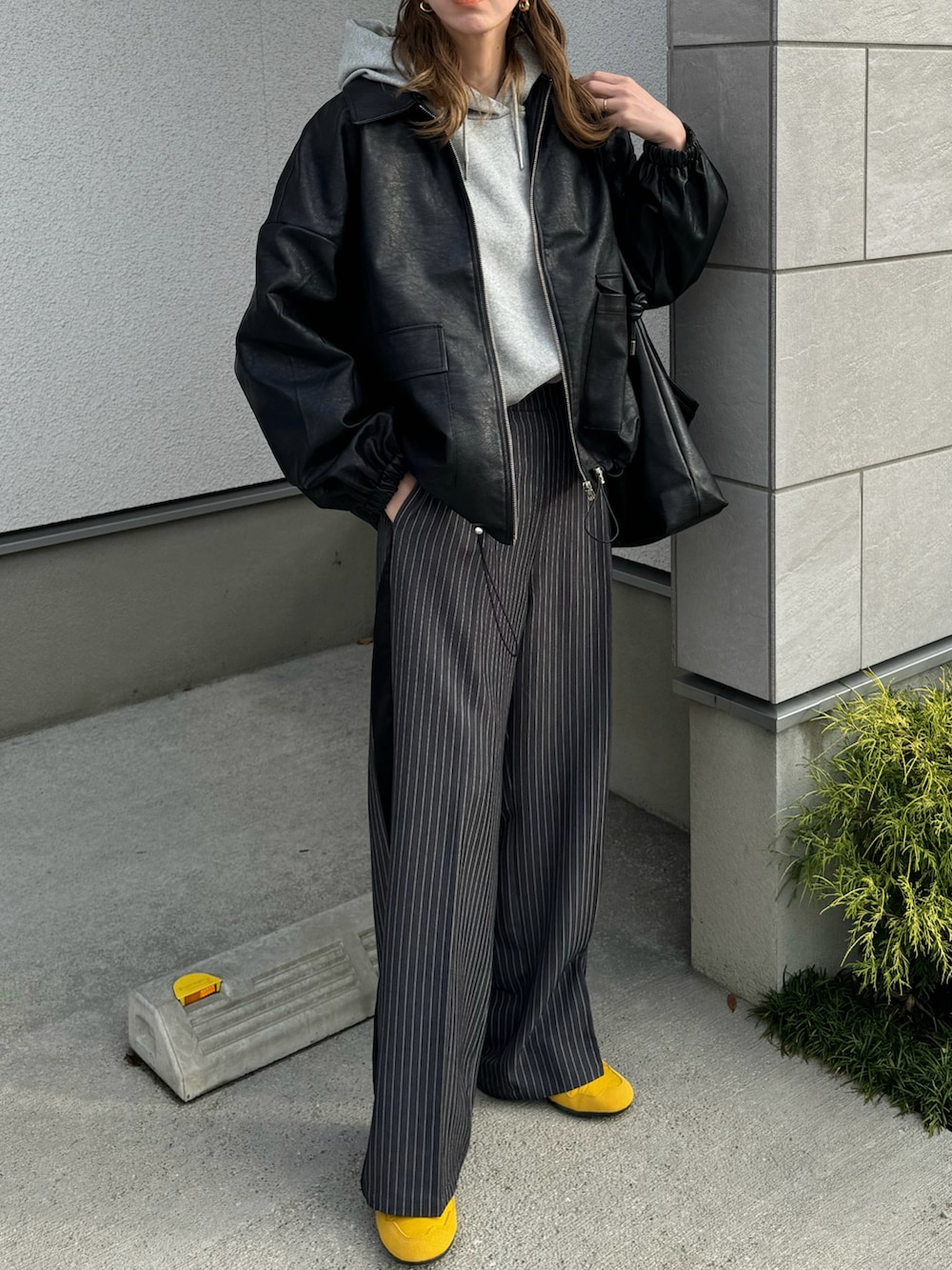 ブラック系のブルゾン、グレー系のスラックス、イエロー系のスニーカーを着用したレディースの秋コーディネートの2枚目の写真