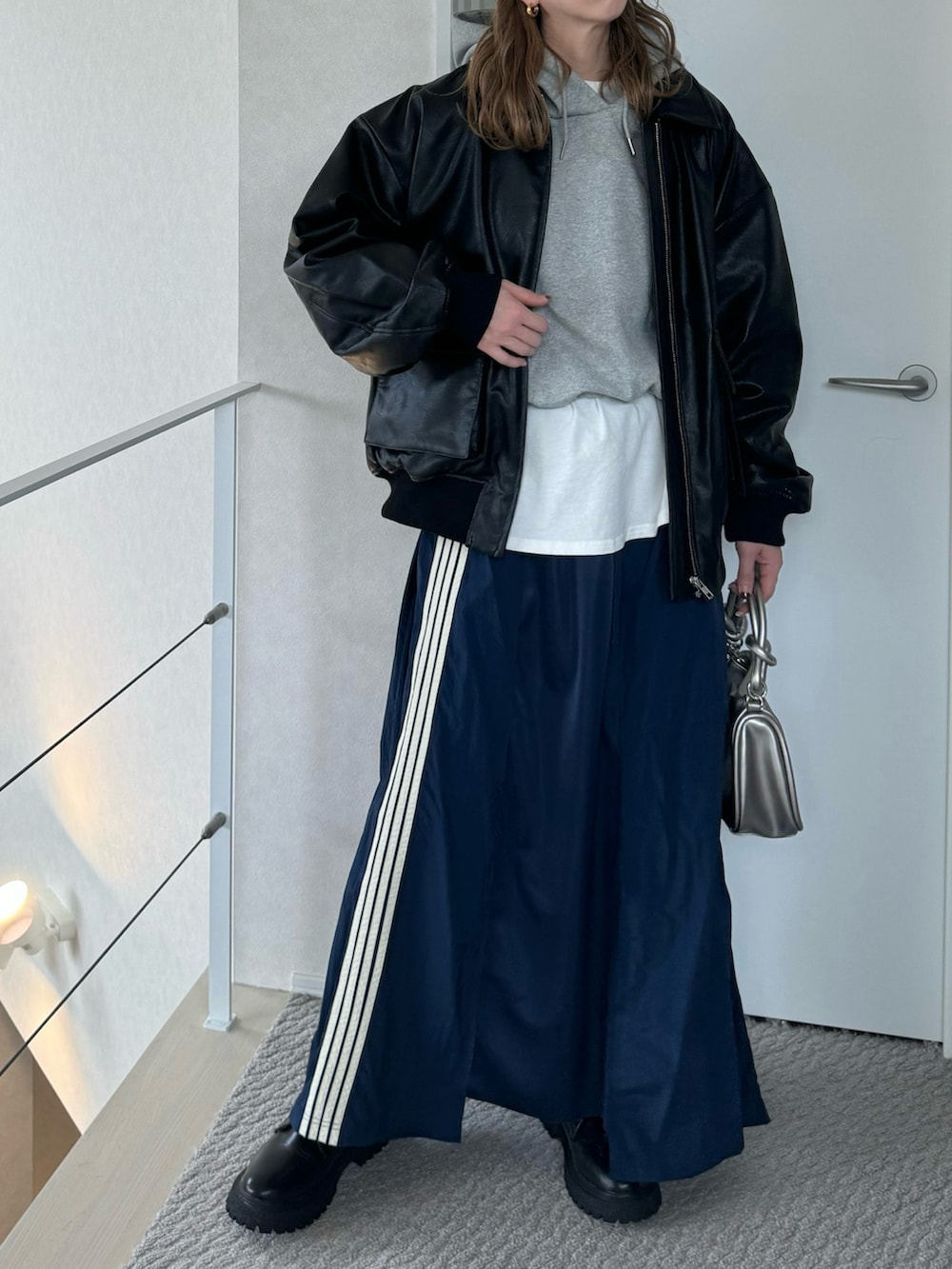 ブラック系のブルゾン、シルバー系のショルダーバッグ、ブルー系のスカートを着用したレディースの冬コーディネートの2枚目の写真